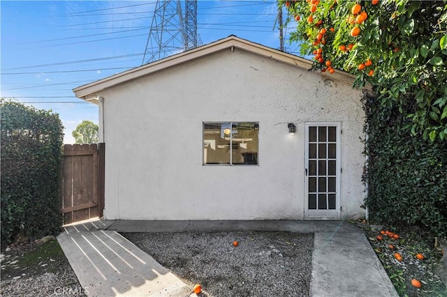 view of side of home with fence and stucco siding