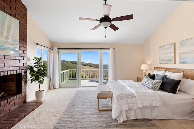 carpeted bedroom featuring lofted ceiling, a brick fireplace, access to outside, and a ceiling fan