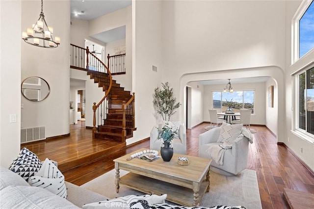 living area featuring wood finished floors, visible vents, stairway, and an inviting chandelier