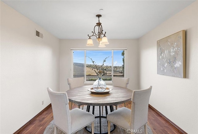 dining space with visible vents, dark wood finished floors, baseboards, and an inviting chandelier