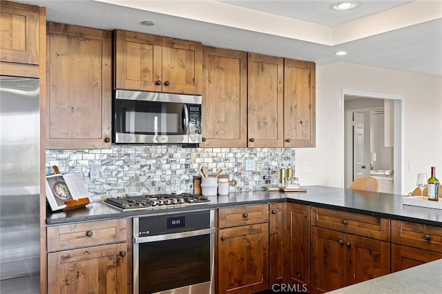 kitchen with appliances with stainless steel finishes, dark countertops, and brown cabinetry