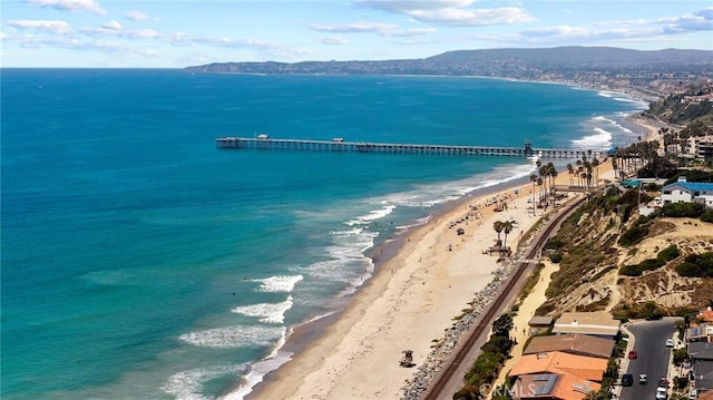 drone / aerial view featuring a view of the beach and a water and mountain view