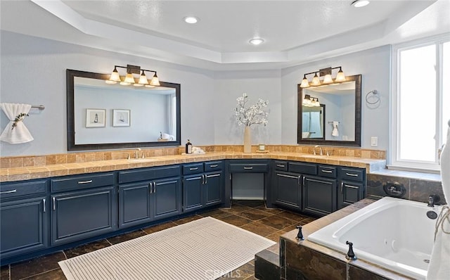 bathroom featuring recessed lighting, vanity, a bath, stone finish floor, and a raised ceiling