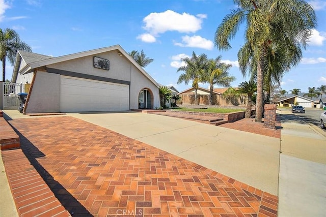 view of front of home featuring concrete driveway, fence, an attached garage, and stucco siding