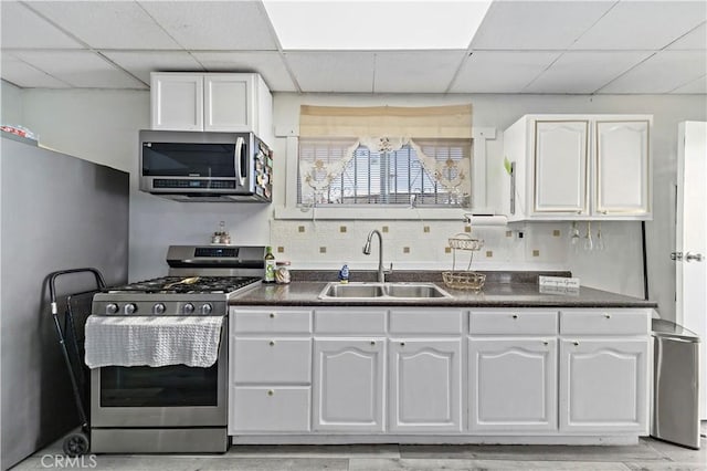 kitchen with dark countertops, appliances with stainless steel finishes, white cabinets, and a sink