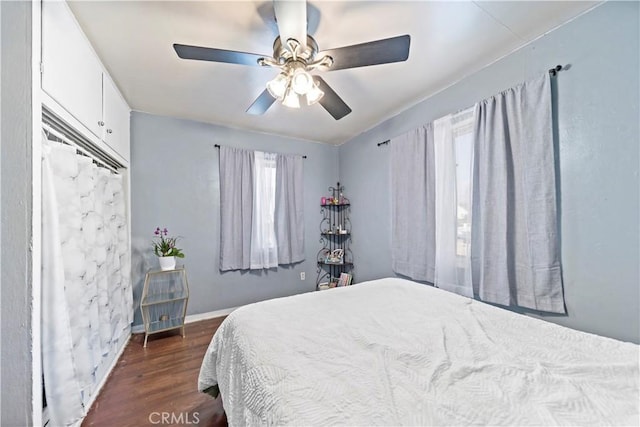 bedroom with ceiling fan, baseboards, and dark wood-style flooring