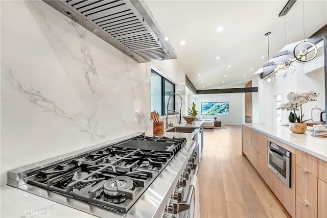 kitchen featuring light wood finished floors, wall oven, light brown cabinets, modern cabinets, and stovetop