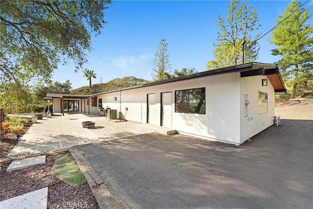 rear view of house featuring a patio, an outdoor fire pit, central AC, and stucco siding