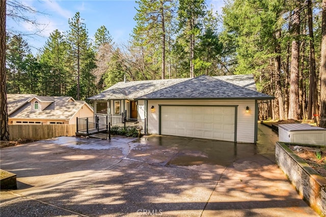 ranch-style home with a garage, driveway, and roof with shingles