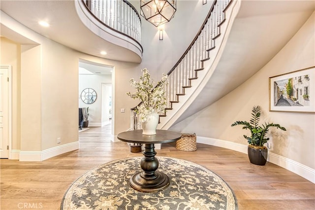 foyer entrance with recessed lighting, stairway, a high ceiling, wood finished floors, and baseboards