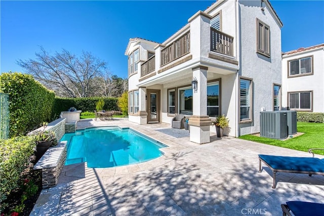 back of house with central AC unit, a fenced in pool, a balcony, a patio area, and stucco siding