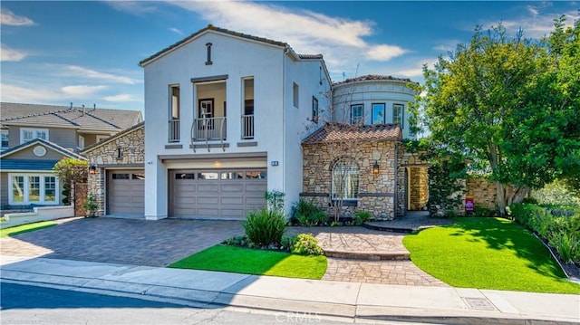 mediterranean / spanish-style home featuring decorative driveway, stucco siding, an attached garage, a balcony, and a front lawn