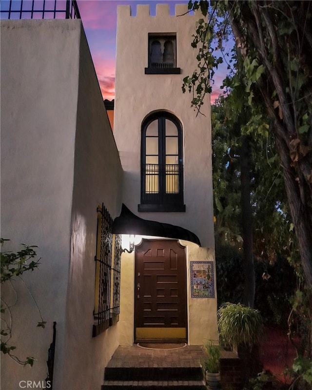 exterior entry at dusk featuring stucco siding