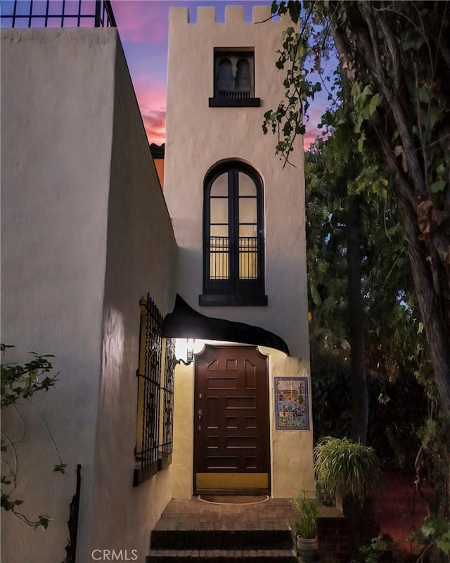 exterior entry at dusk featuring stucco siding
