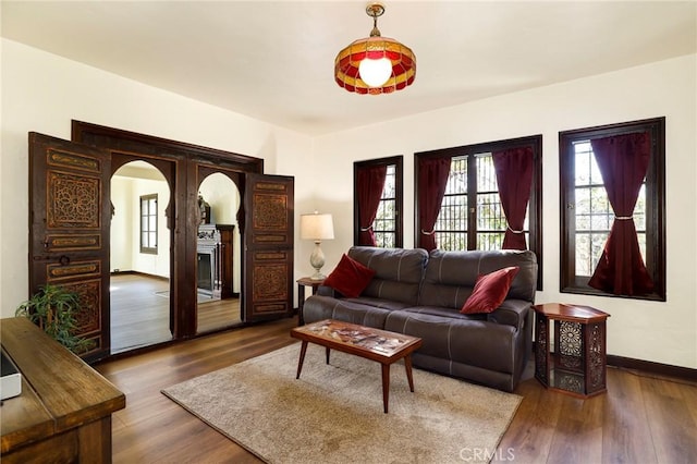 living room featuring baseboards, arched walkways, and wood finished floors
