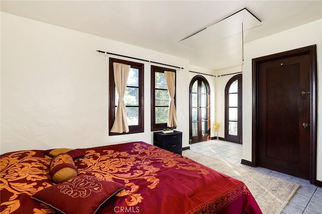 bedroom featuring light tile patterned floors, baseboards, and attic access