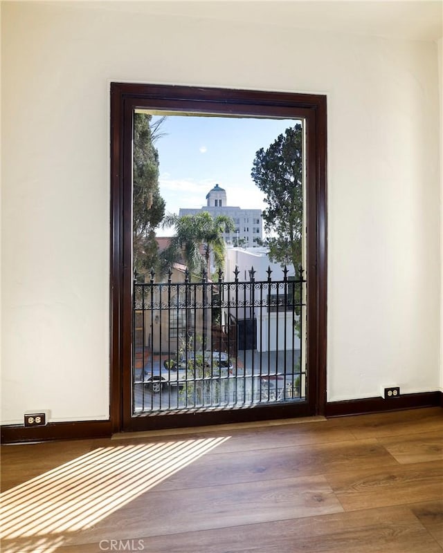 doorway with a city view, baseboards, and wood finished floors