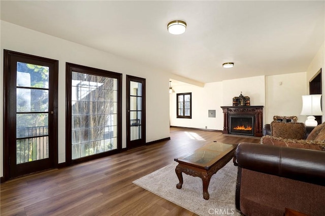 living room with a fireplace with flush hearth, baseboards, and dark wood finished floors