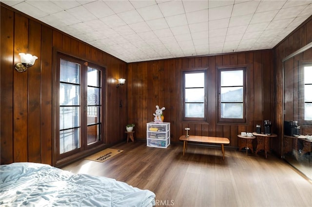 bedroom featuring wood walls, multiple windows, and wood finished floors
