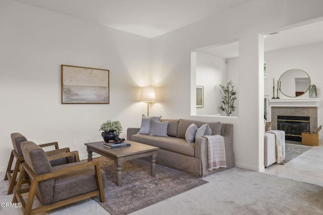 living area featuring baseboards, a glass covered fireplace, and light colored carpet