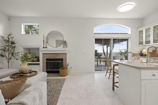 living area featuring a fireplace with flush hearth and baseboards