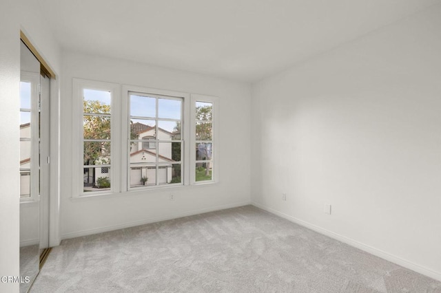 unfurnished room with baseboards and light colored carpet