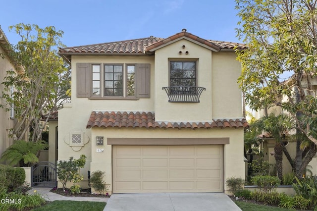 mediterranean / spanish-style home with concrete driveway, an attached garage, a tiled roof, and stucco siding