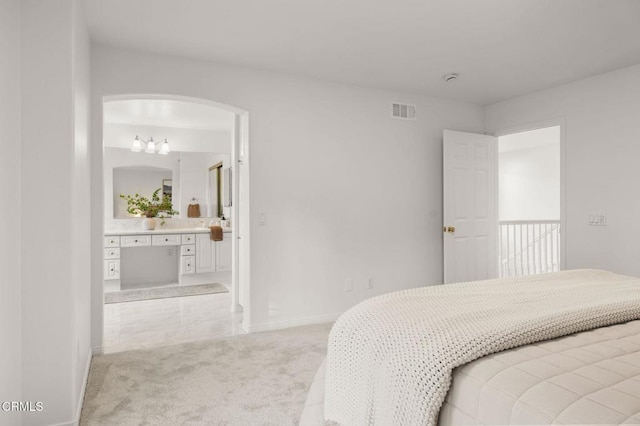 bedroom with light carpet, ensuite bath, baseboards, and visible vents