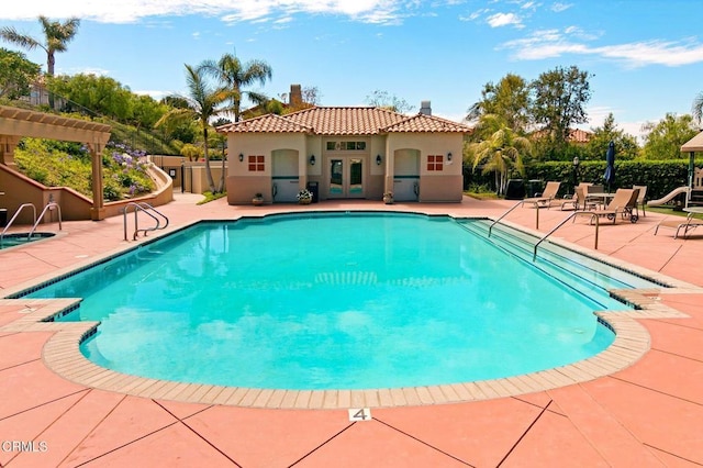 community pool with a patio area, fence, and french doors