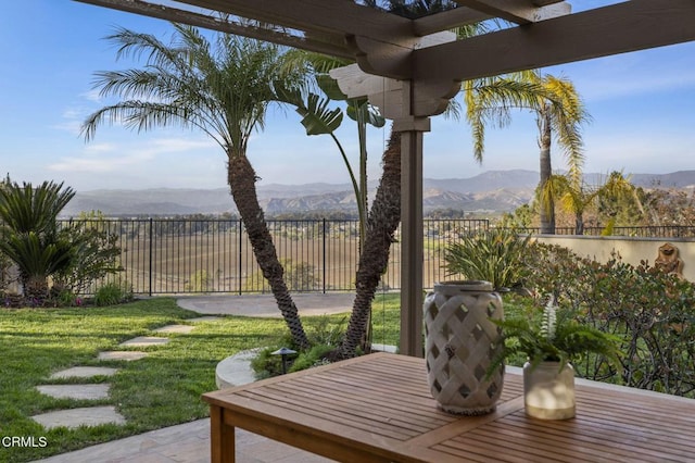 wooden terrace featuring a yard, a patio area, a fenced backyard, and a mountain view