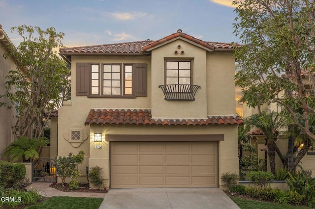 mediterranean / spanish-style house with a garage, a tile roof, driveway, and stucco siding