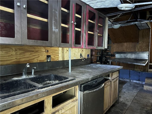 kitchen with dark countertops, glass insert cabinets, a sink, and dishwasher
