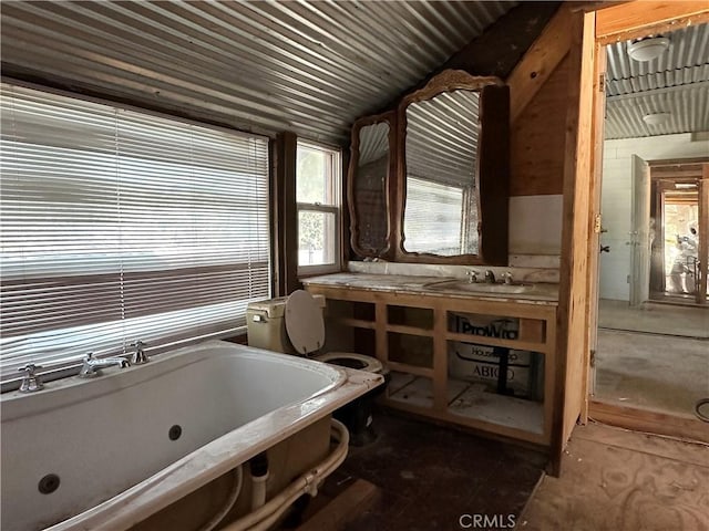 bathroom featuring vanity, vaulted ceiling, toilet, and a tub to relax in