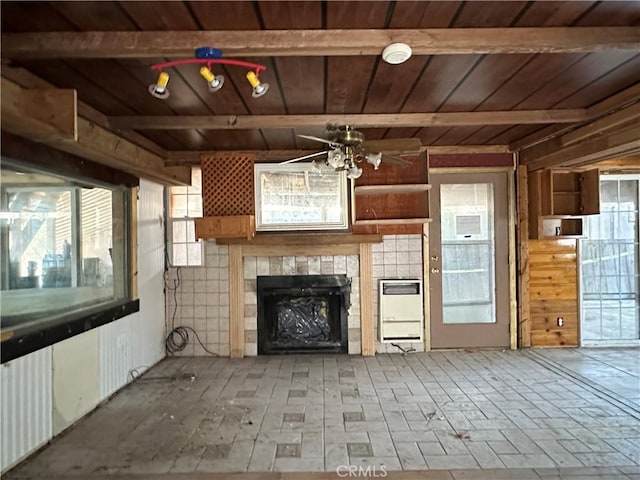 unfurnished living room featuring a tiled fireplace, wooden ceiling, ceiling fan, and a wealth of natural light
