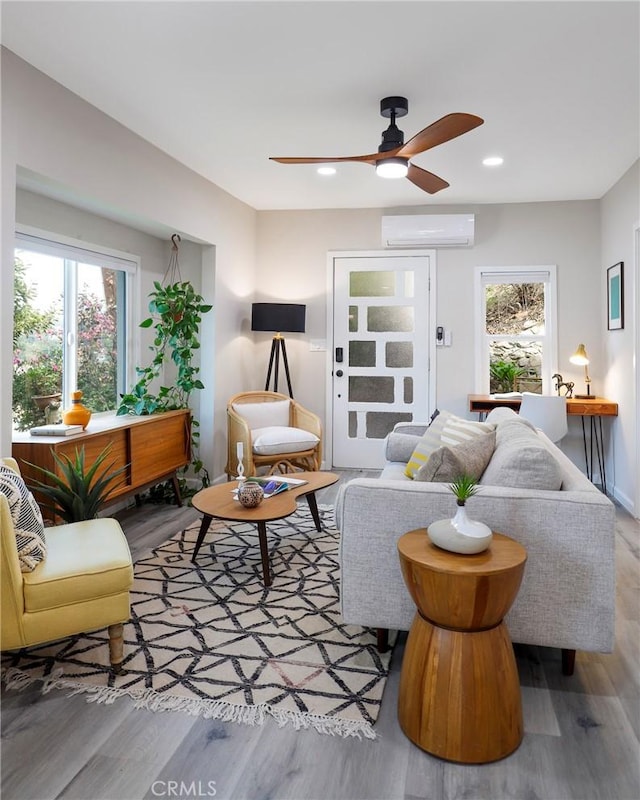 living area with recessed lighting, a wall mounted air conditioner, wood finished floors, and a healthy amount of sunlight