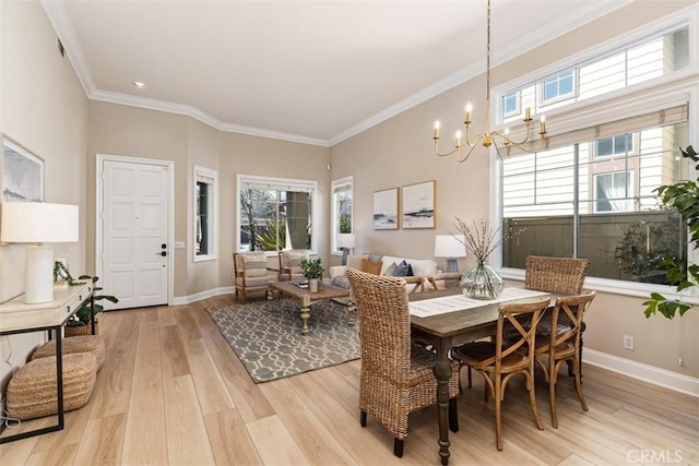 dining room with a notable chandelier, light wood-style flooring, baseboards, and crown molding