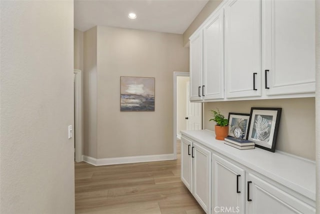 hall with light wood finished floors, baseboards, and recessed lighting