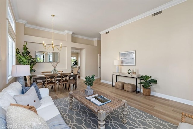 living room with a healthy amount of sunlight, ornamental molding, a notable chandelier, and wood finished floors