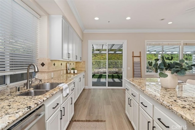 kitchen featuring crown molding, light wood finished floors, decorative backsplash, a sink, and dishwasher