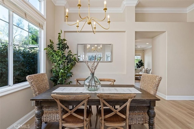 dining space featuring a chandelier, ornamental molding, light wood-style flooring, and baseboards