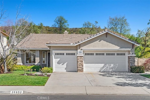 ranch-style house featuring stone siding, concrete driveway, a chimney, and an attached garage