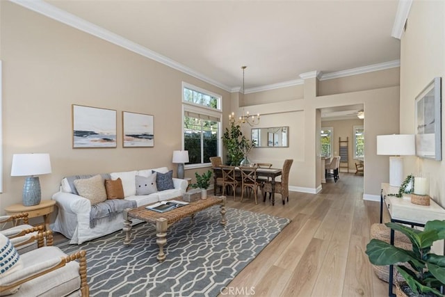 living room with ornamental molding, a notable chandelier, light wood-style flooring, and baseboards