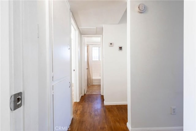 hallway featuring dark wood-style flooring and baseboards