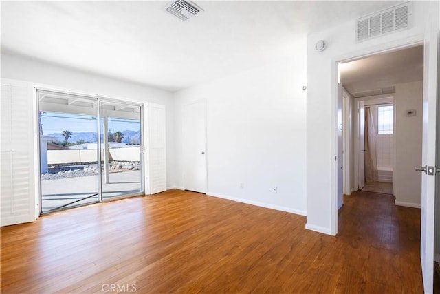 unfurnished room featuring visible vents, baseboards, and wood finished floors