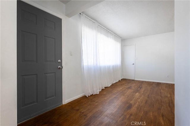 unfurnished room featuring beamed ceiling, dark wood finished floors, and baseboards