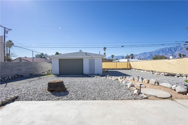 view of yard featuring a garage, a fenced backyard, a mountain view, and driveway