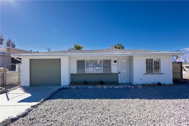 ranch-style house featuring a garage, driveway, fence, and stucco siding