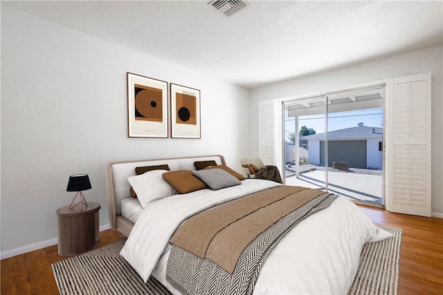 bedroom with access to outside, visible vents, baseboards, and wood finished floors