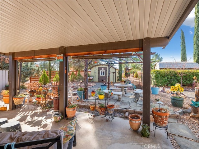 view of patio with an outbuilding, fence, outdoor dining space, and a storage unit