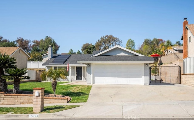 ranch-style house featuring driveway, a garage, solar panels, fence, and stucco siding